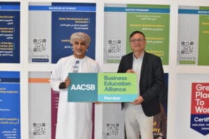 Two men holding a AACSB Board